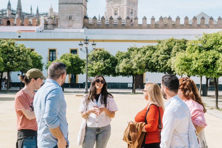 Group of people chatting in front of a historic building with a tall, ornate tower.