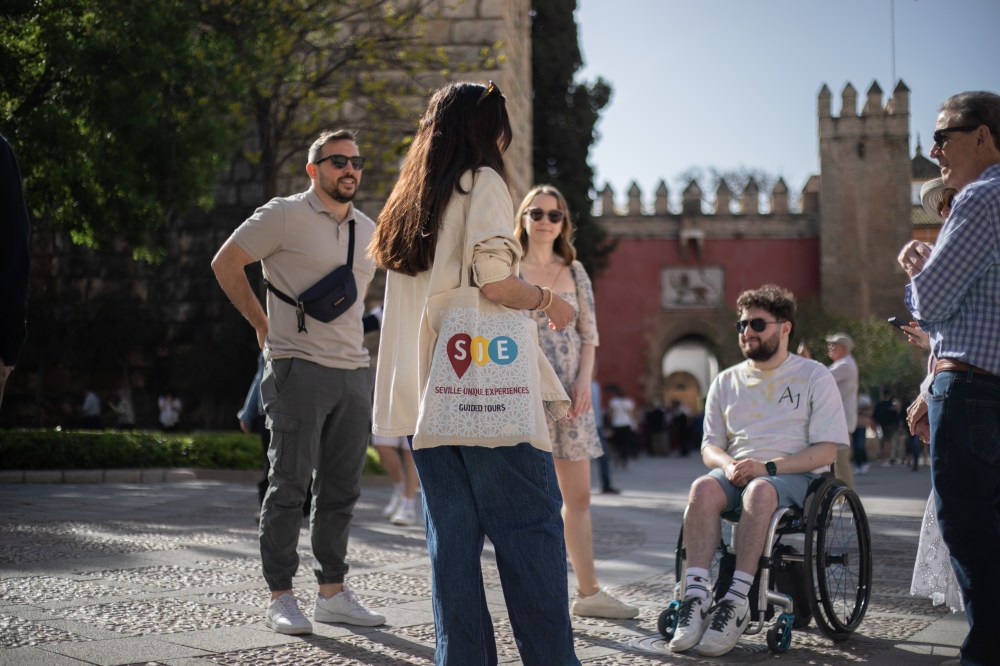 People in a sunny outdoor setting, with one person using a wheelchair.