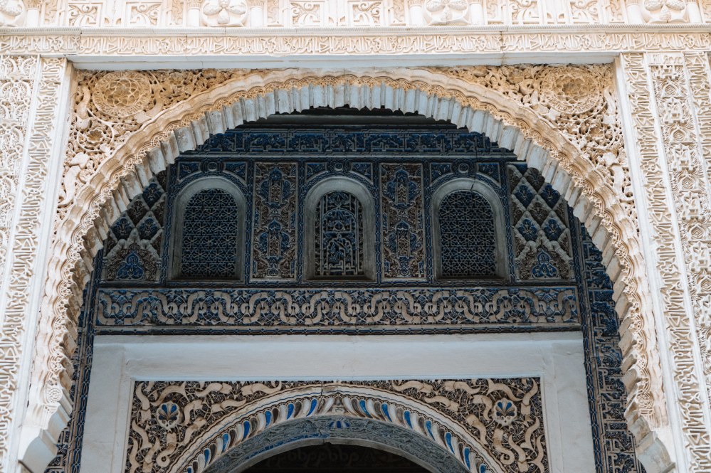 Intricate archway at Seville Alcazar with detailed carvings and patterns in a historical building.