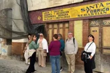Group of people standing on cobblestone street near old shopfront.