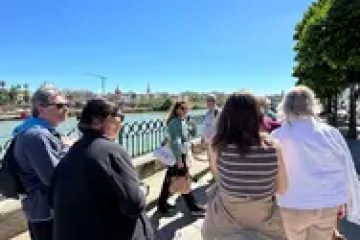 Group of people walking by a riverside under a clear blue sky.
