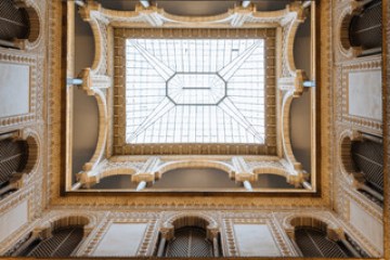 Ornate atrium ceiling with glass skylight and arched balconies.
