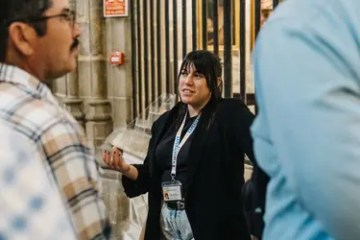Woman giving a tour in a building, speaking to a group of people.