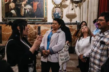 Guide talking to a group in a museum with paintings on the wall.