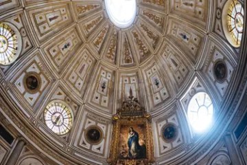 Ornate church dome interior with circular windows and a religious painting.