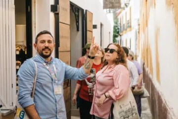 Tour guide leading a group, gesturing on a narrow street.
